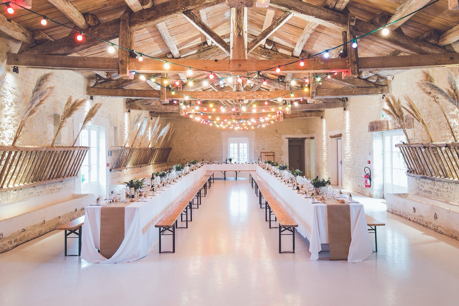 Bright wedding reception room prepared with long tables and string lights